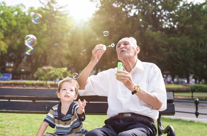 Großvater und Enkel machen Seifblasen im Park