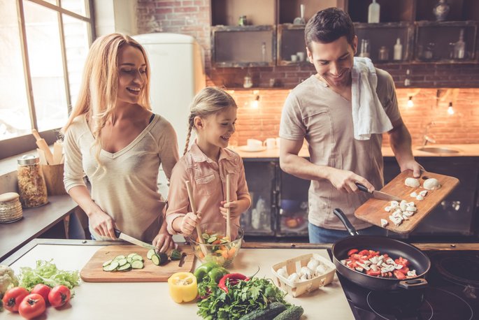 Familie mit Kind beim Kochen am heimischen Herd